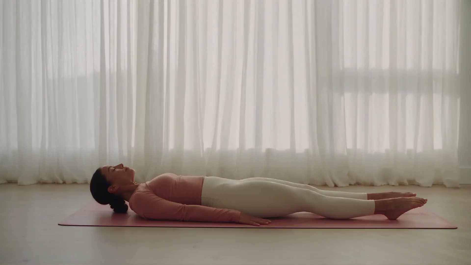 Une pratiquante réalise un mouvement de Pilates dans le studio lumineux